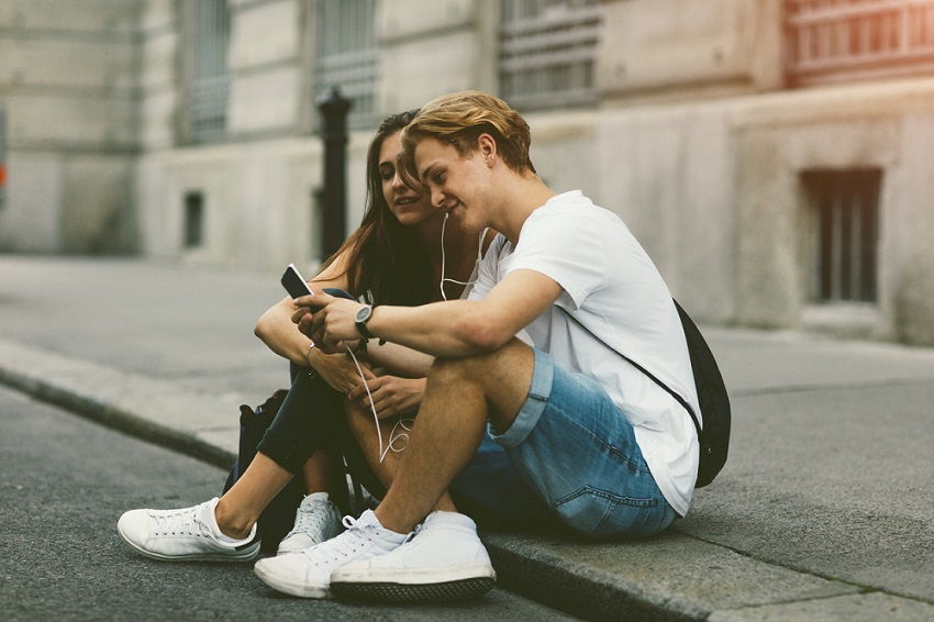 Una pareja de adolescentes usando auriculares en la calle