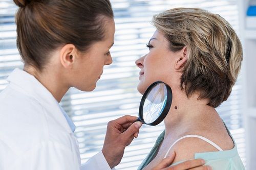 Una doctora revisa un lunar en el cuello de una mujer