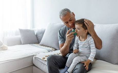 Un padre usa un inhalador para tratar el asma de su hijo