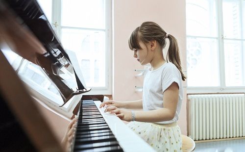 Una niña toca el piano como actividad extraescolar