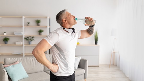Un hombre bebiendo agua después de hacer ejercicio
