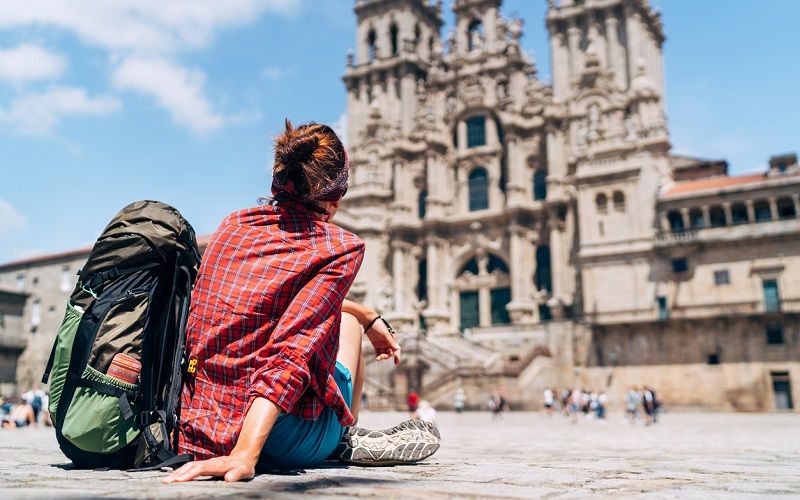 Una mujer sentada en frente de la catedral de Santiago de Compostela